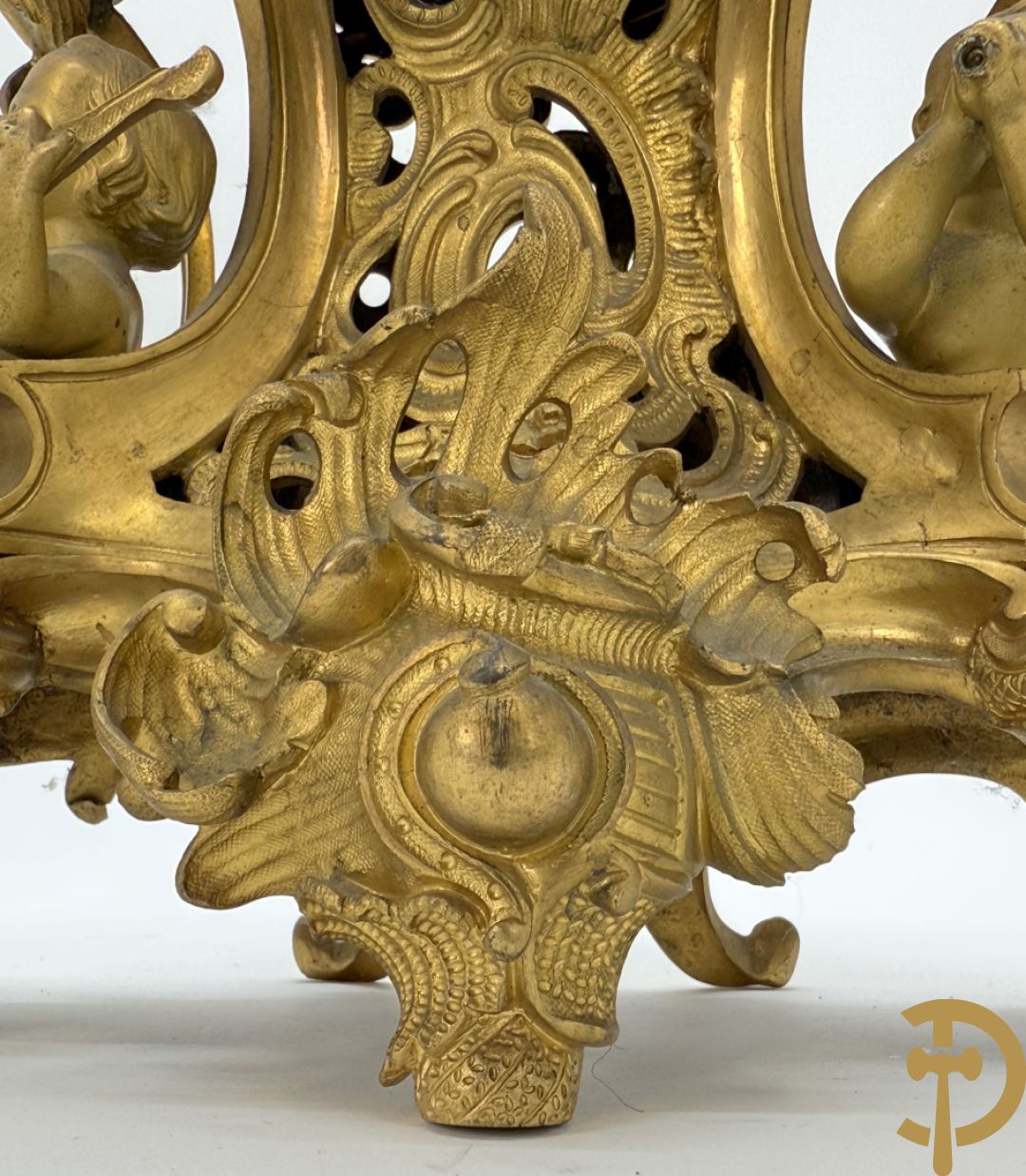Driedelige vuurvergulde bronzen garnituur, Louis XV stijl, bestaande uit middenstuk met klok omgeven door musicerende cupido