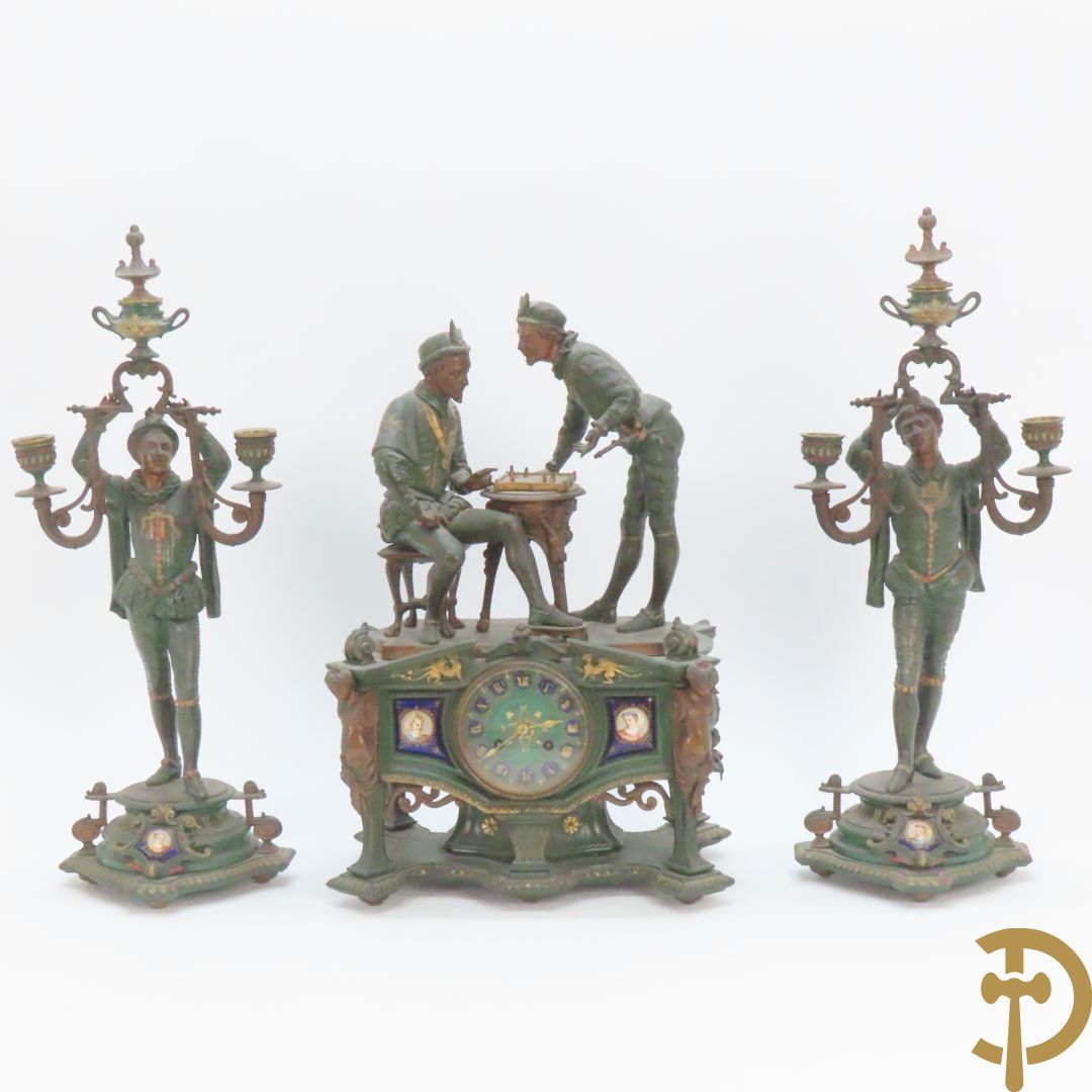 Driedelige kunstbronzen garnituur bestaande uit pendule met paar schakende edelheren, bezet met kariatiden - geflankeerd door paar driearmige kandelaars gehouden door 2 edelheren