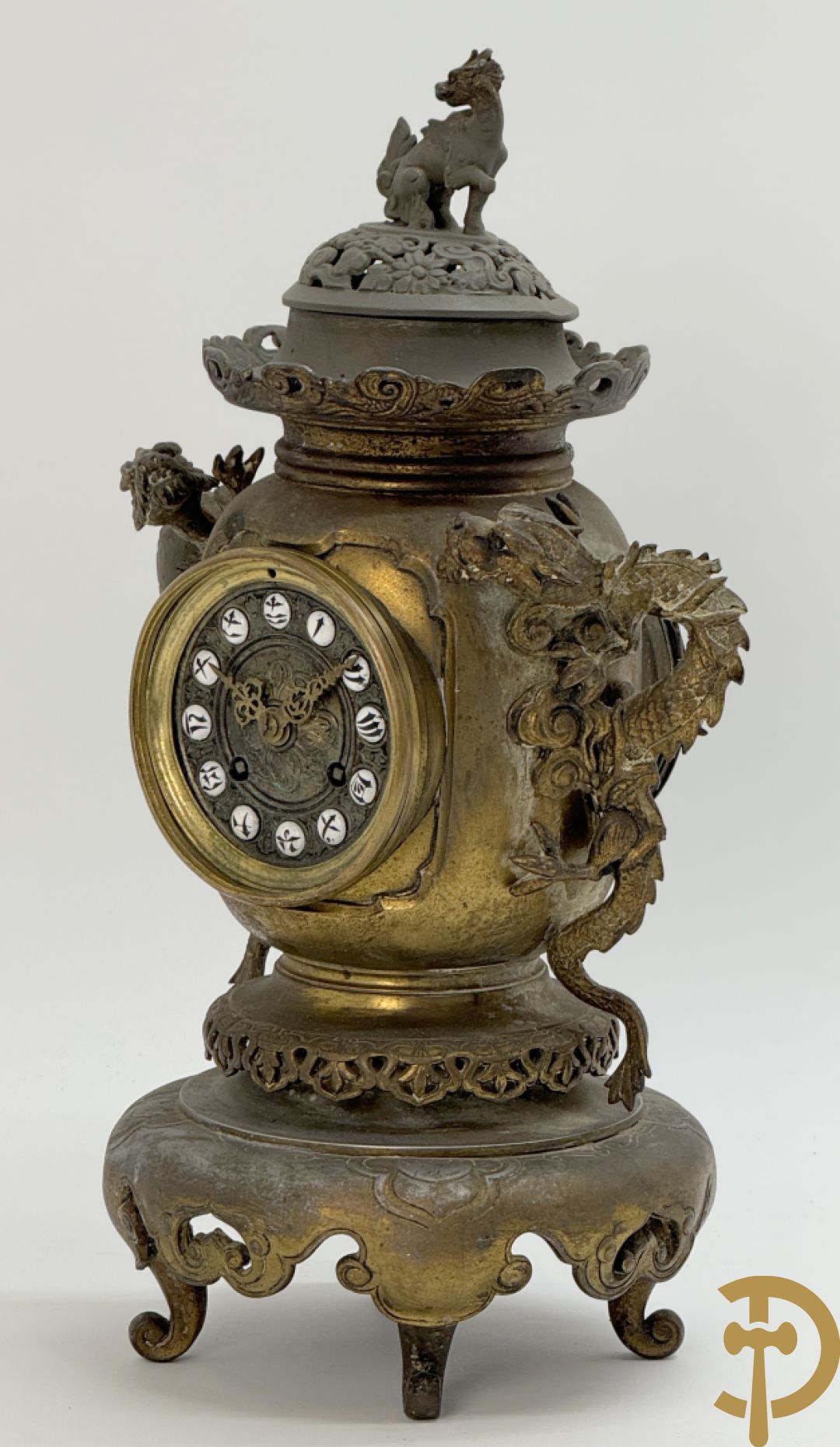 Aziatische pendule in zamak, zijdelings bezet met drakendecor en bovenaan met mythologisch figuur