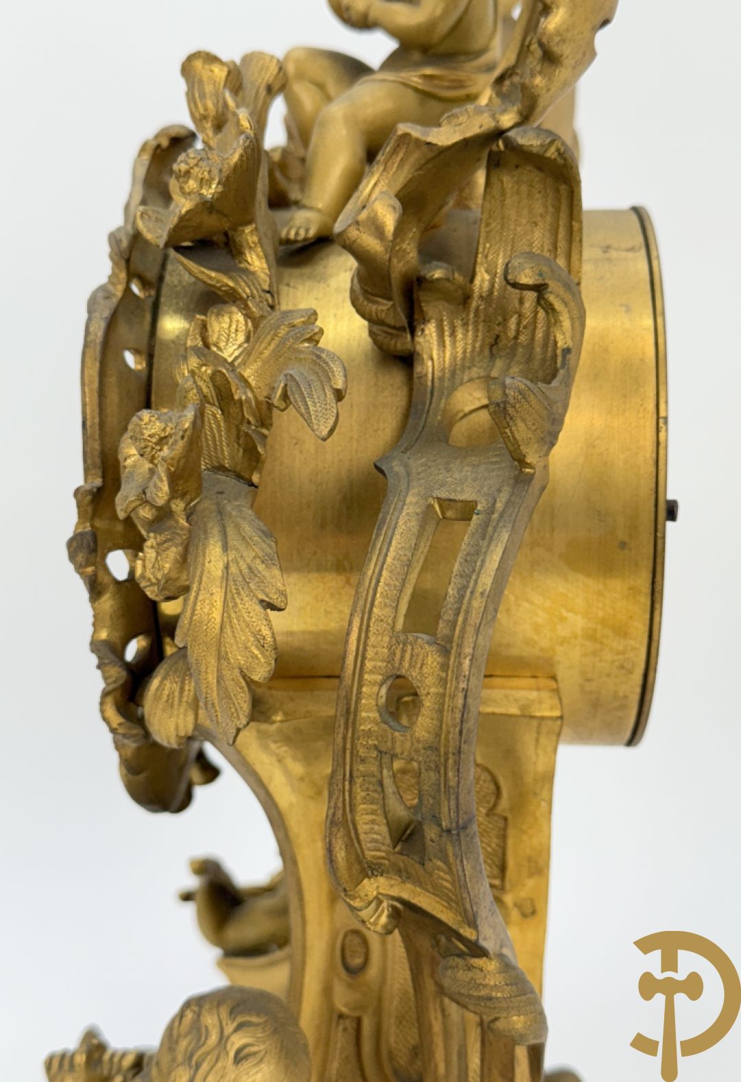 Driedelige vuurvergulde bronzen garnituur, Louis XV stijl, bestaande uit middenstuk met klok omgeven door musicerende cupido