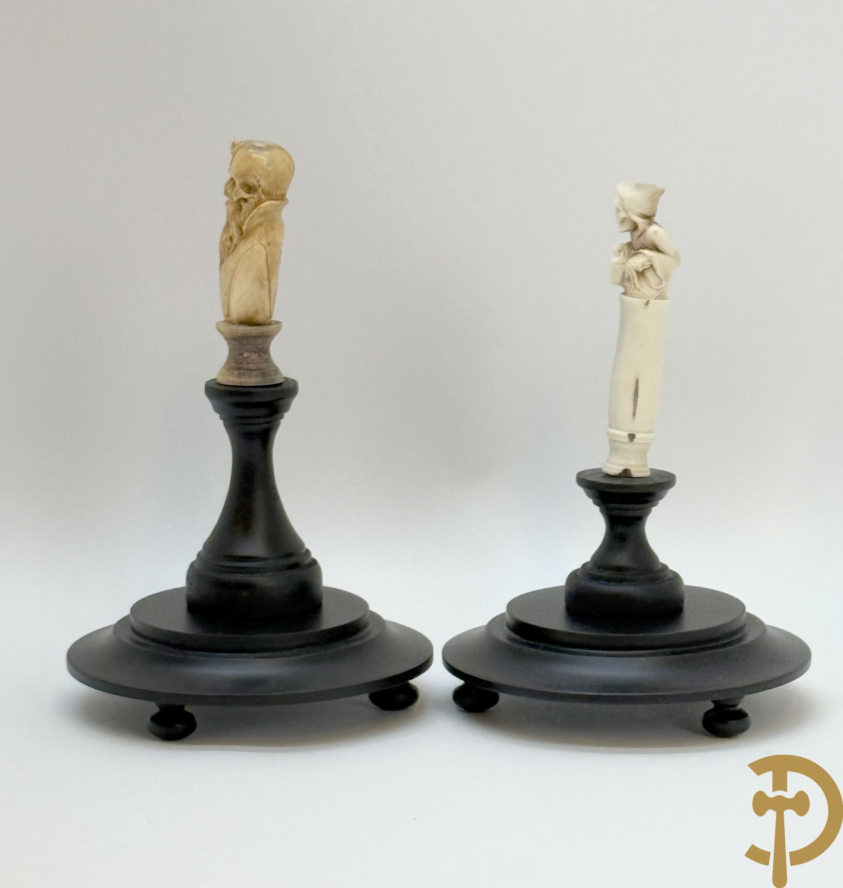 Twee handgesculpteerde hertegeweien in de vorm van een doodskop onder globe