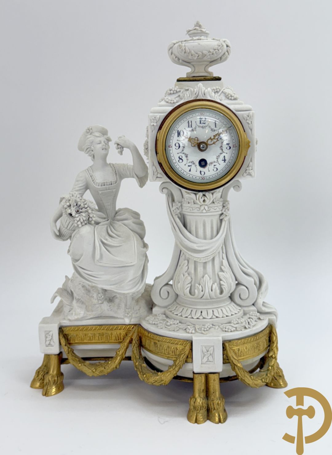 Driedelige porseleinen garnituur met bronsbeslag bestaande uit pendule met dame en amfoor geflankeerd door paar kandelaars bezet met personages