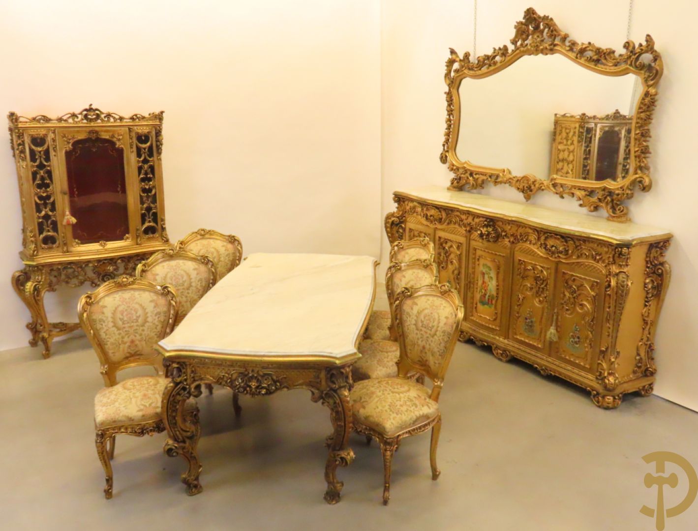 Uitzonderlijke vergulde Louis XV eetkamer bestaande uit vijfdeursdressoir met voluutvormige accanthusranken en rocailles, beschilderd met bloemenmotieven en centraal tafererel met hoornen des overvloeds + bijhorende spiegel vergulde tafel op voluutvormige poten met zes bijhorende stoelen + vitrine met accanthusranken en centrale deur, op voluutvormige poten