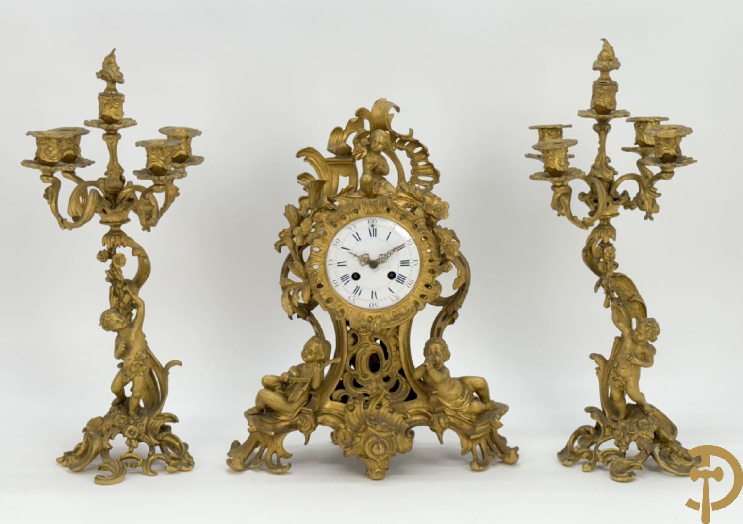 Driedelige vuurvergulde bronzen garnituur, Louis XV stijl, bestaande uit middenstuk met klok omgeven door musicerende cupido