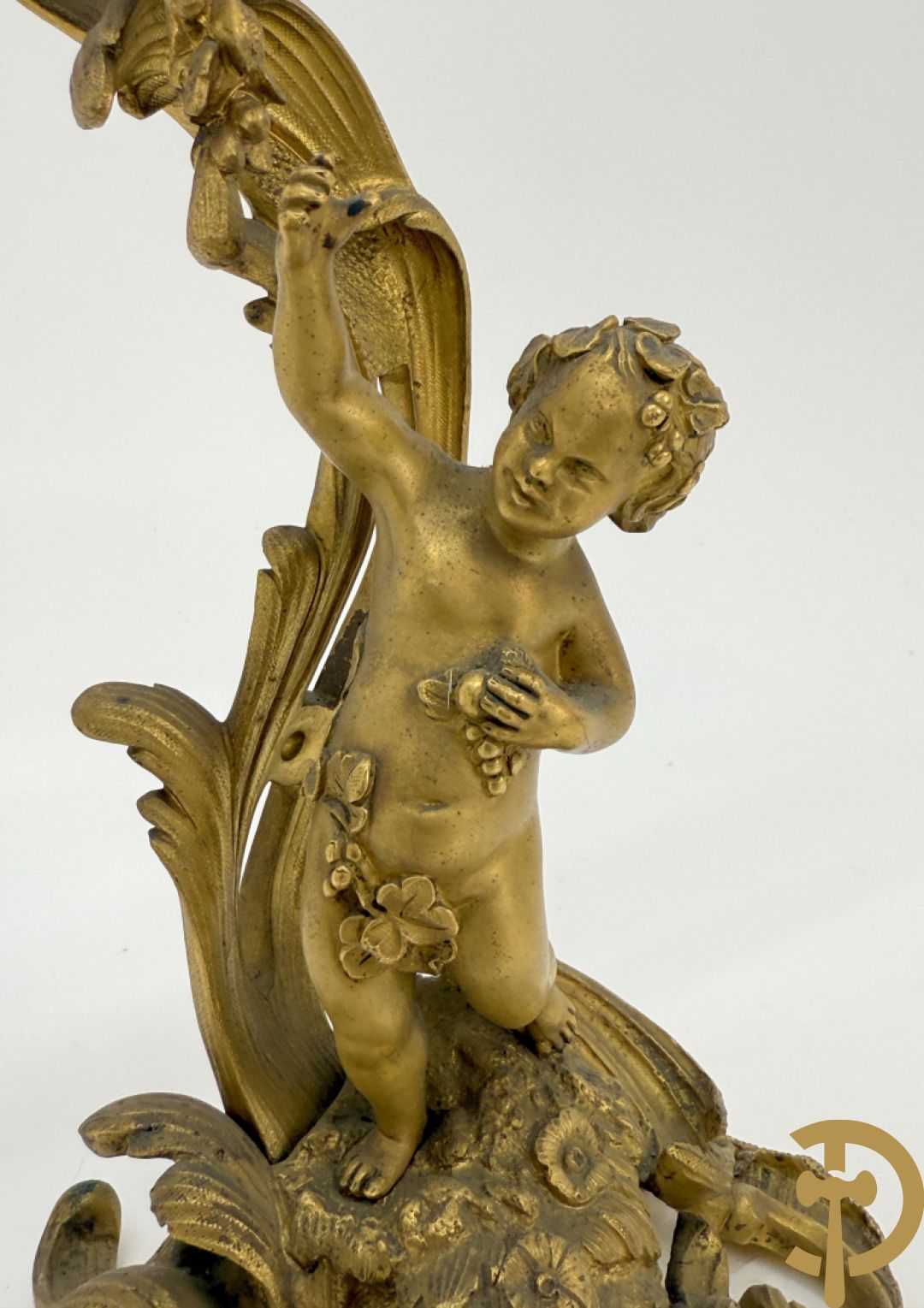 Driedelige vuurvergulde bronzen garnituur, Louis XV stijl, bestaande uit middenstuk met klok omgeven door musicerende cupido