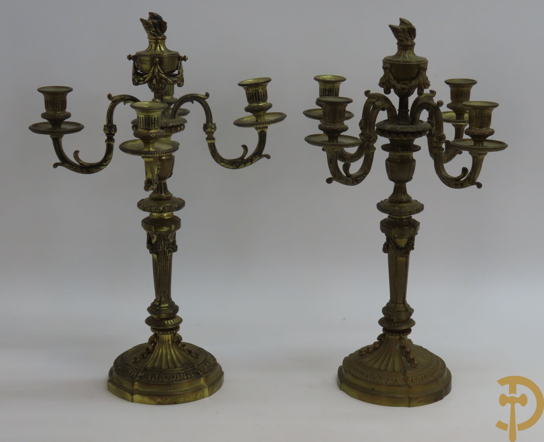 Paar bronzen Louis XVI vierarmige kandelaars bezet met toorts bovenaan