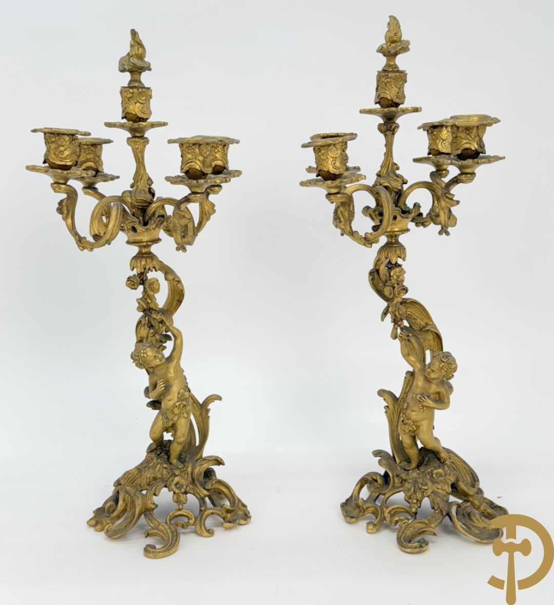 Driedelige vuurvergulde bronzen garnituur, Louis XV stijl, bestaande uit middenstuk met klok omgeven door musicerende cupido