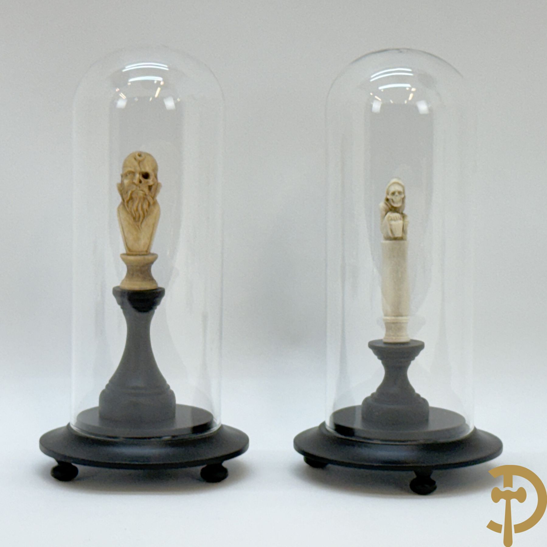 Twee handgesculpteerde hertegeweien in de vorm van een doodskop onder globe