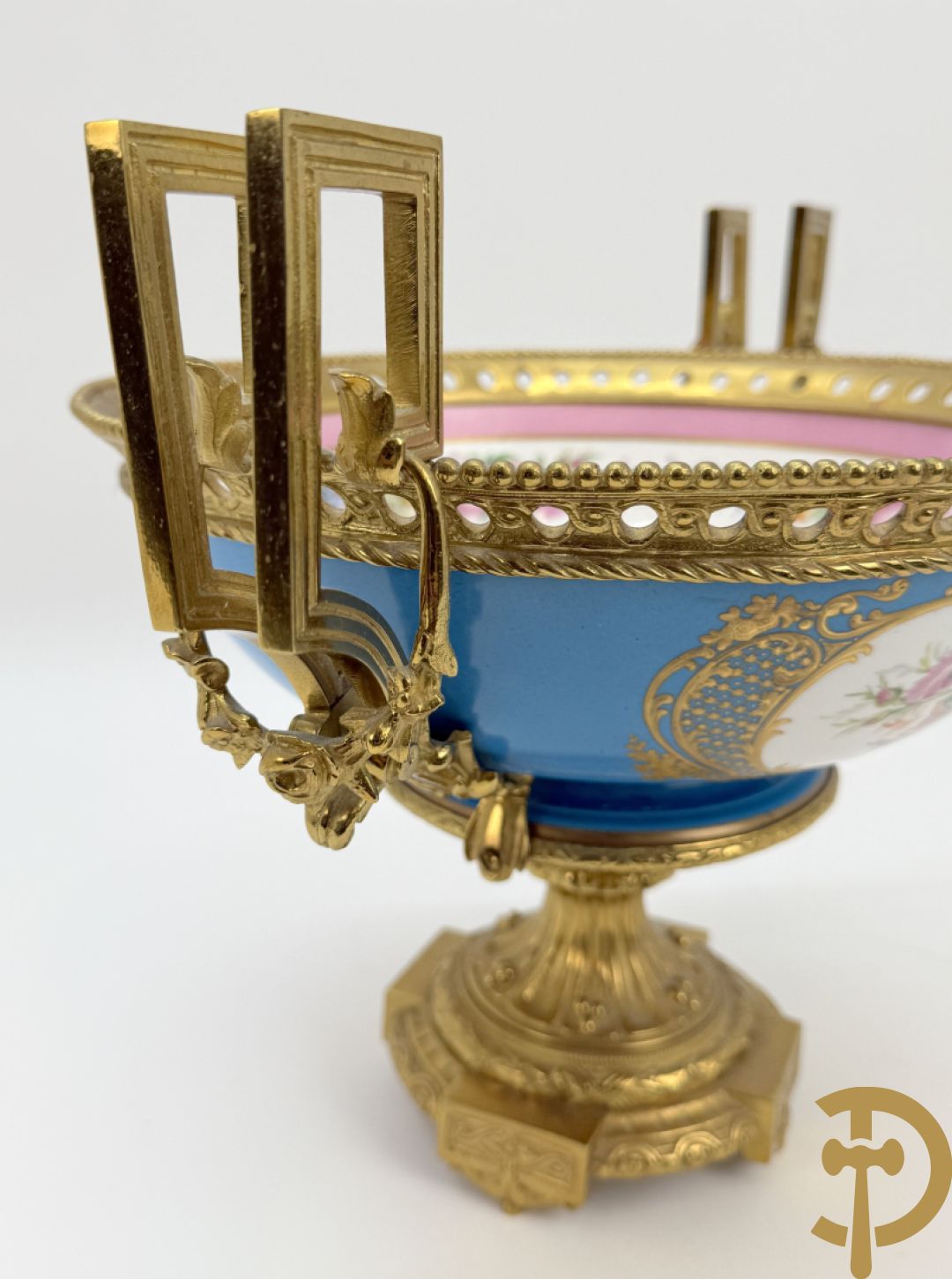 Porseleinen coupe met centraal tafereel en omringd met bloemendecor, gevat in bronzen houder