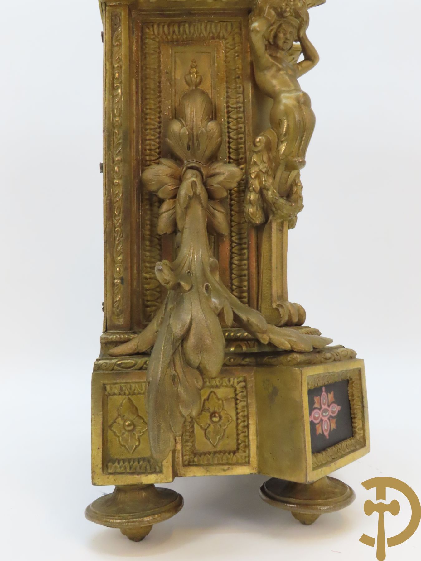 Vergulde pendule in zamak, wijzerplaat bezet met porseleinen plakkettes - bovenaan met vogelpaar, zijdelings met kariathyden houdende een bloementroffee - onder glazen stolp