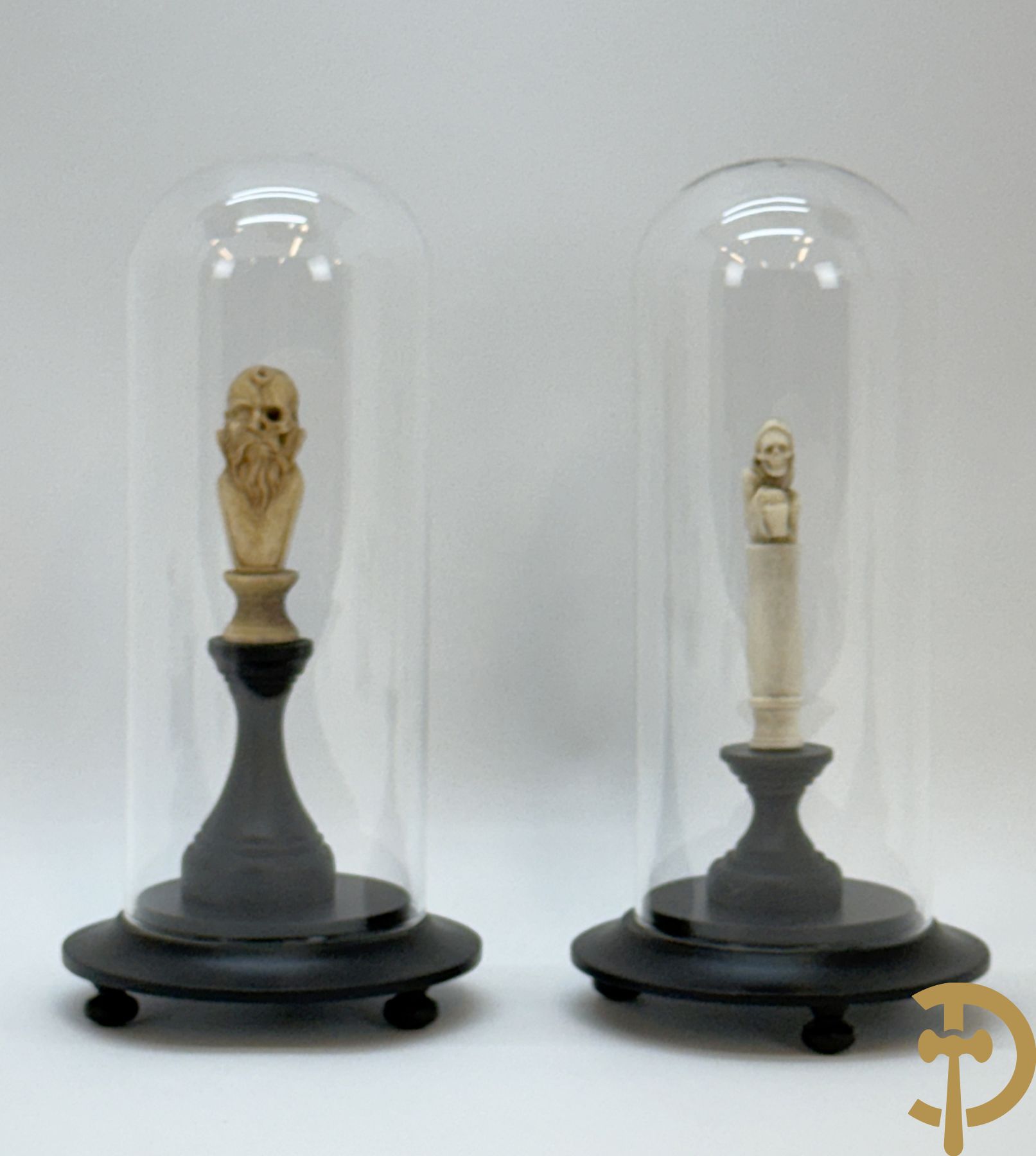 Twee handgesculpteerde hertegeweien in de vorm van een doodskop onder globe