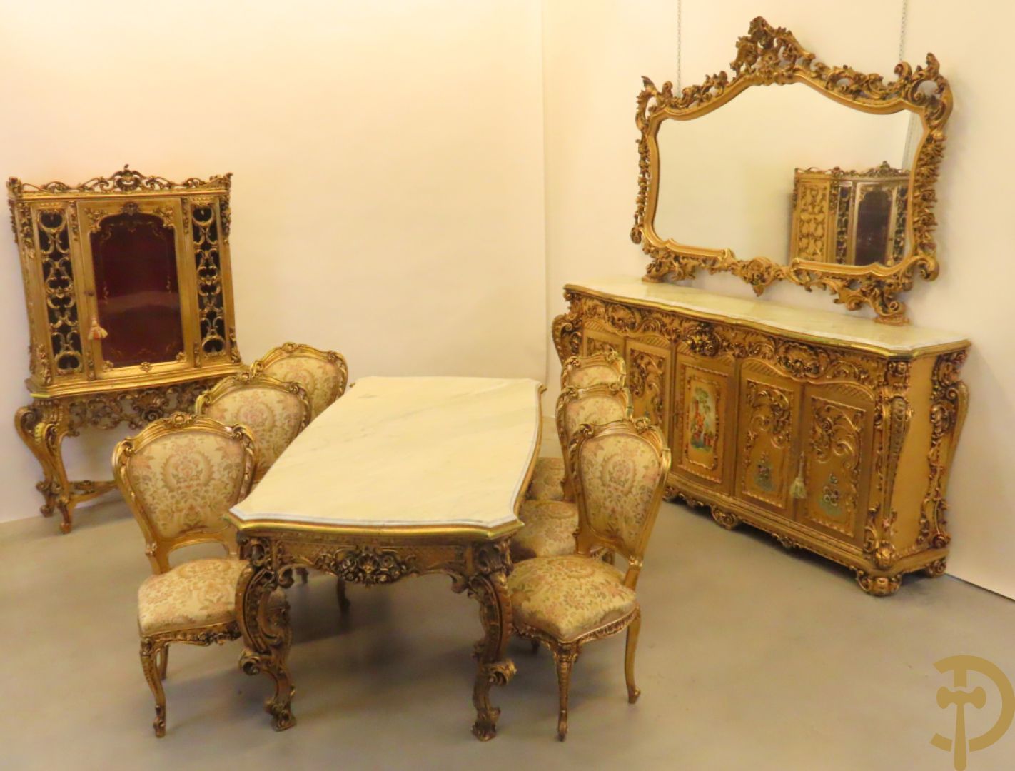 Uitzonderlijke vergulde Louis XV eetkamer bestaande uit vijfdeursdressoir met voluutvormige accanthusranken en rocailles, beschilderd met bloemenmotieven en centraal tafererel met hoornen des overvloeds + bijhorende spiegel vergulde tafel op voluutvormige poten met zes bijhorende stoelen + vitrine met accanthusranken en centrale deur, op voluutvormige poten