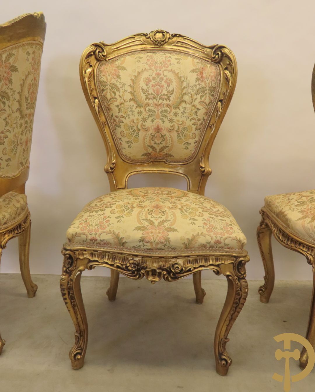 Uitzonderlijke vergulde Louis XV eetkamer bestaande uit vijfdeursdressoir met voluutvormige accanthusranken en rocailles, beschilderd met bloemenmotieven en centraal tafererel met hoornen des overvloeds + bijhorende spiegel vergulde tafel op voluutvormige poten met zes bijhorende stoelen + vitrine met accanthusranken en centrale deur, op voluutvormige poten