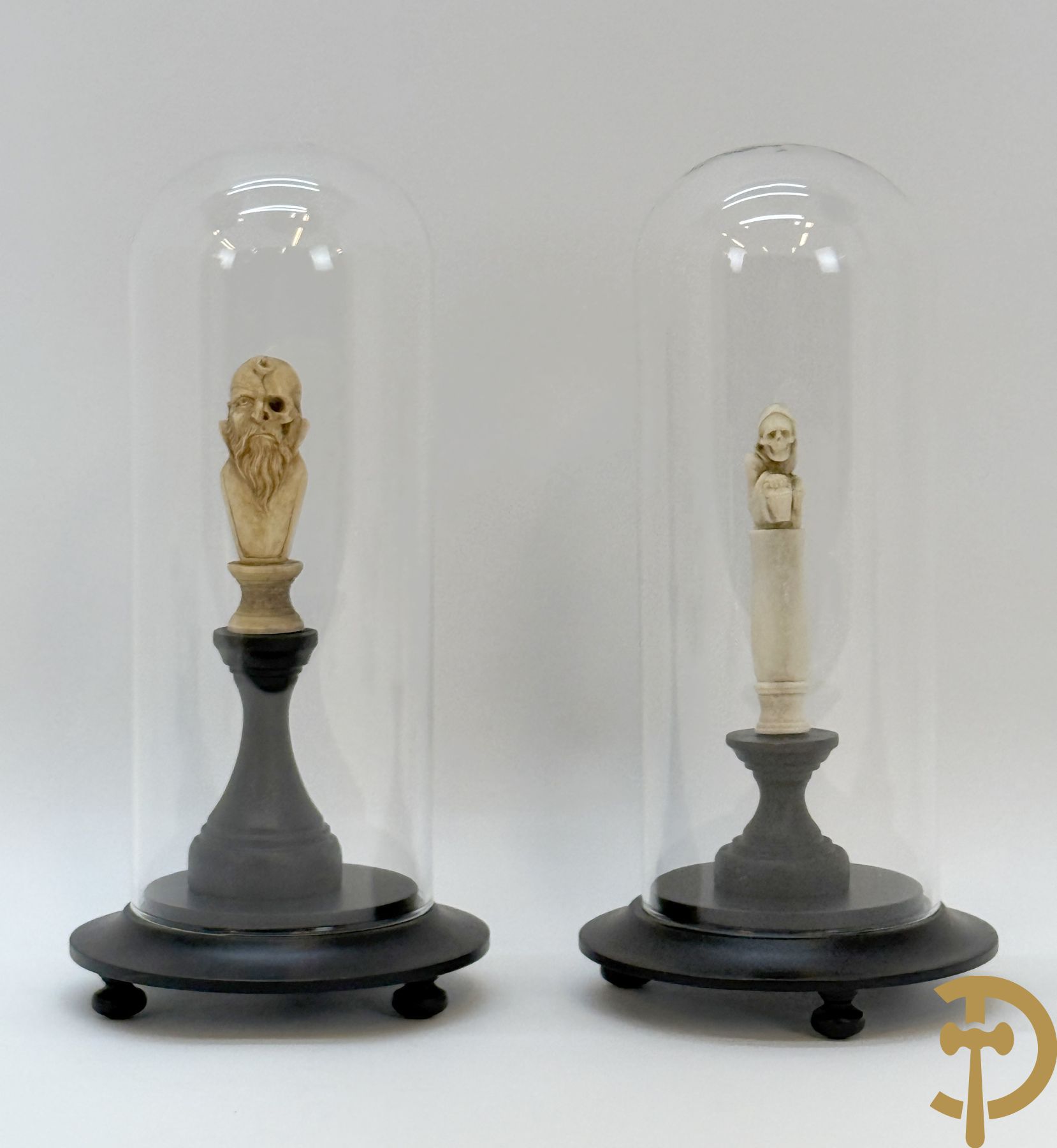 Twee handgesculpteerde hertegeweien in de vorm van een doodskop onder globe