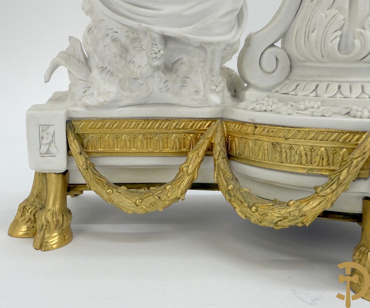 Driedelige porseleinen garnituur met bronsbeslag bestaande uit pendule met dame en amfoor geflankeerd door paar kandelaars bezet met personages