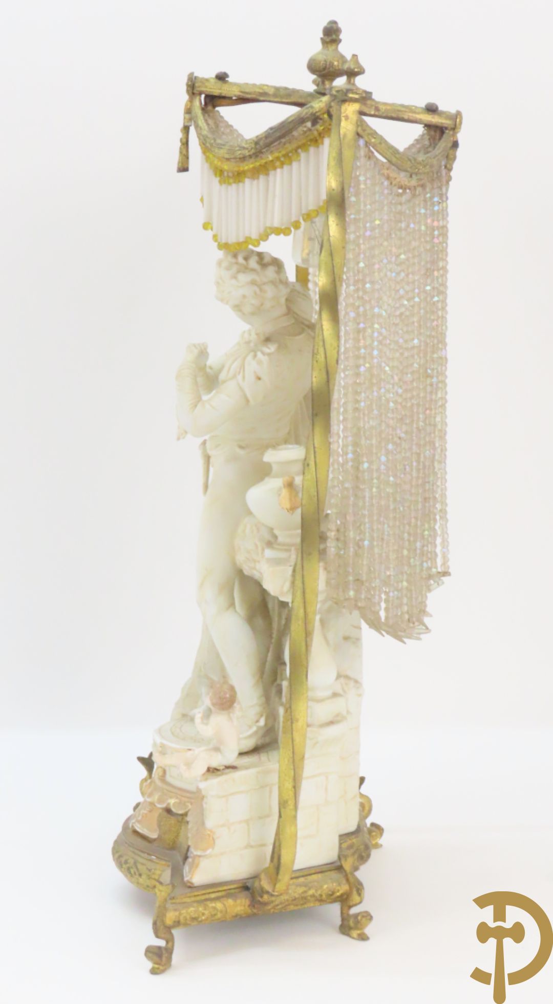 Lieftallig biscuit van romantisch koppel bij amfoor met kleine neergezeten cupido onder koperen baldakijn met kristallen belletjes