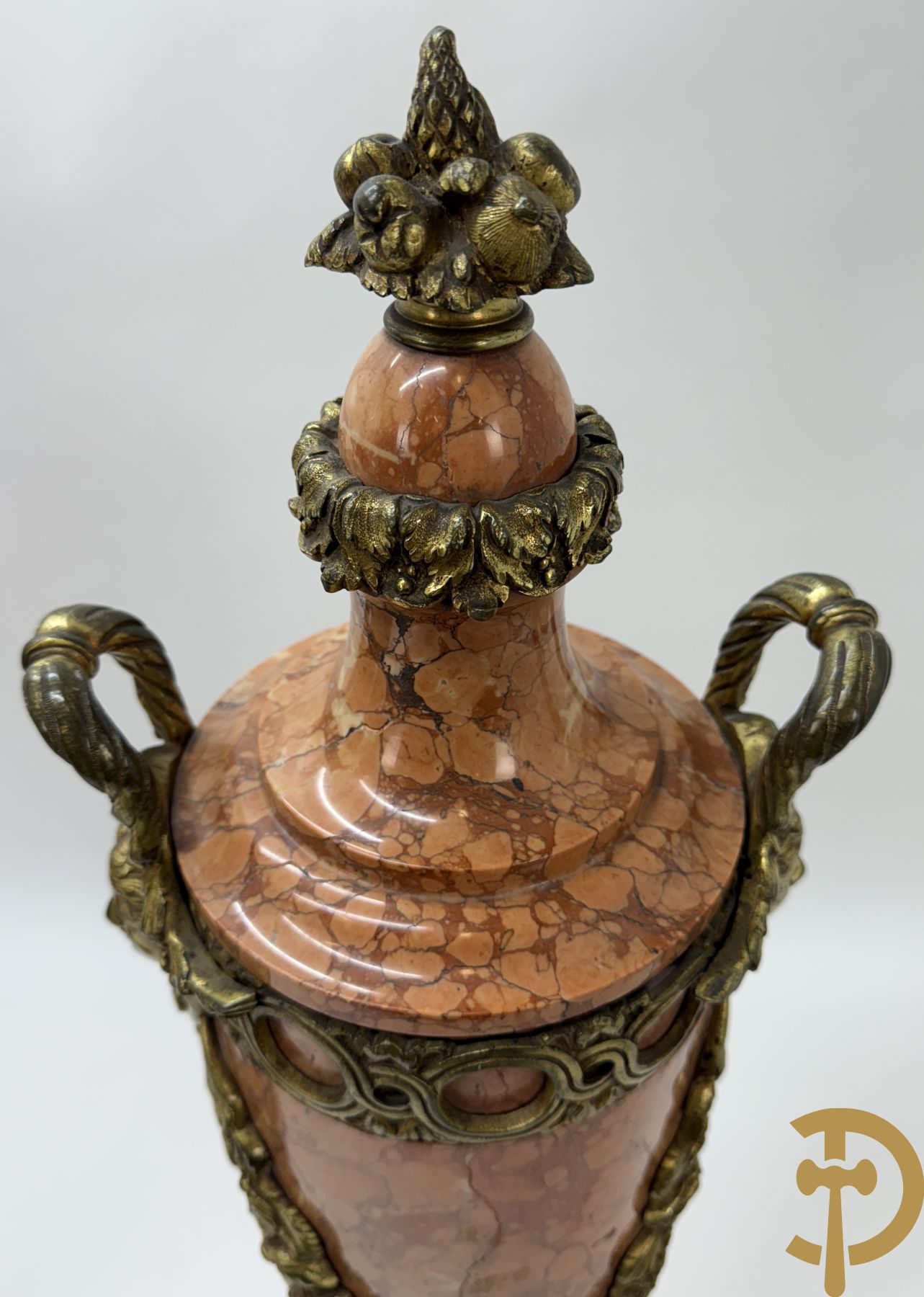 Paar oranje/rode marmeren cassolettes, zijdelings bezet met dameshoofden dragende een guirlande van bloemen - bovenaan met bloementroffee