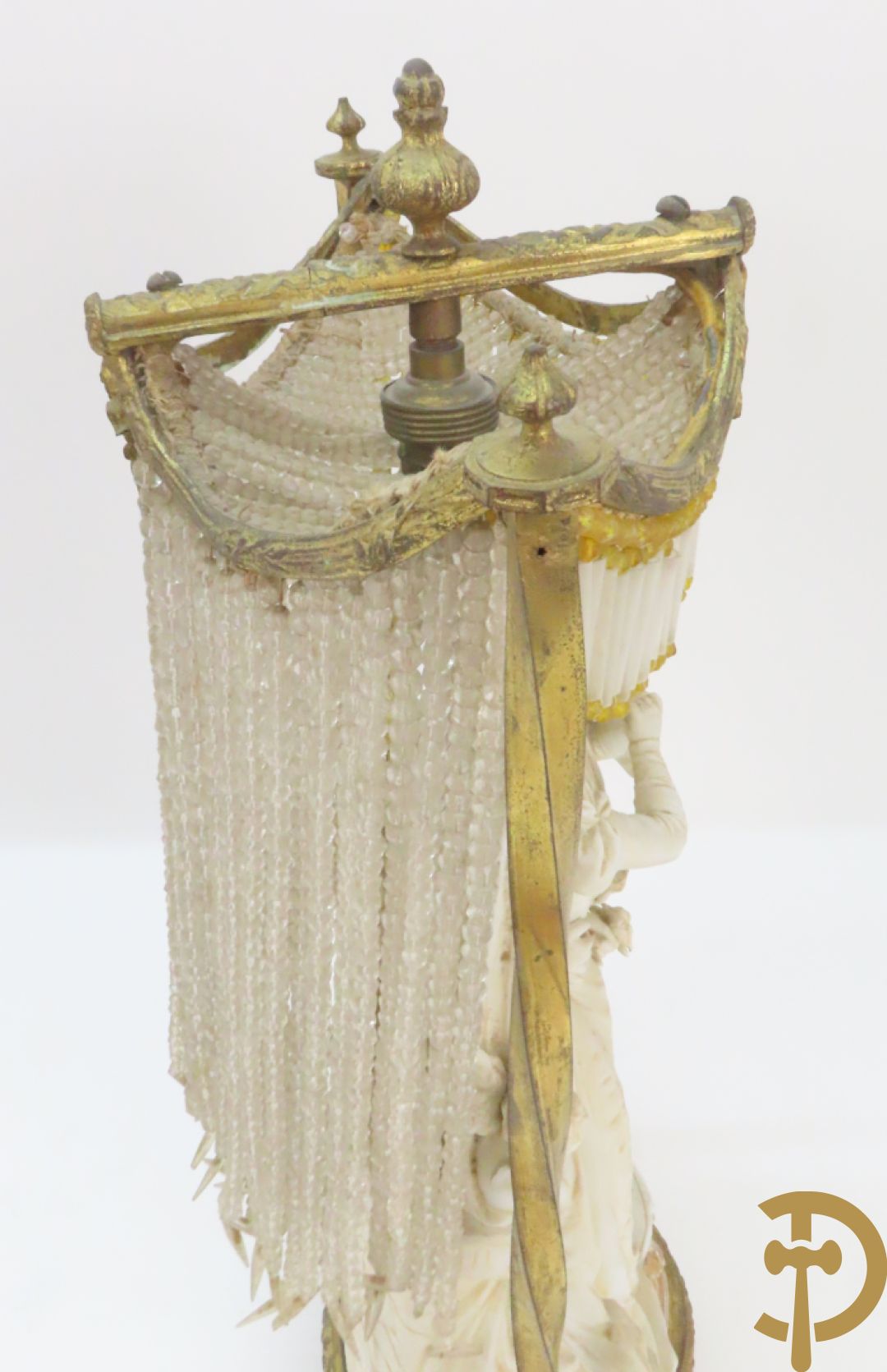 Lieftallig biscuit van romantisch koppel bij amfoor met kleine neergezeten cupido onder koperen baldakijn met kristallen belletjes