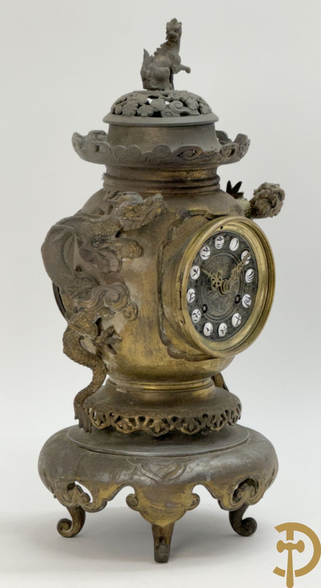 Aziatische pendule in zamak, zijdelings bezet met drakendecor en bovenaan met mythologisch figuur