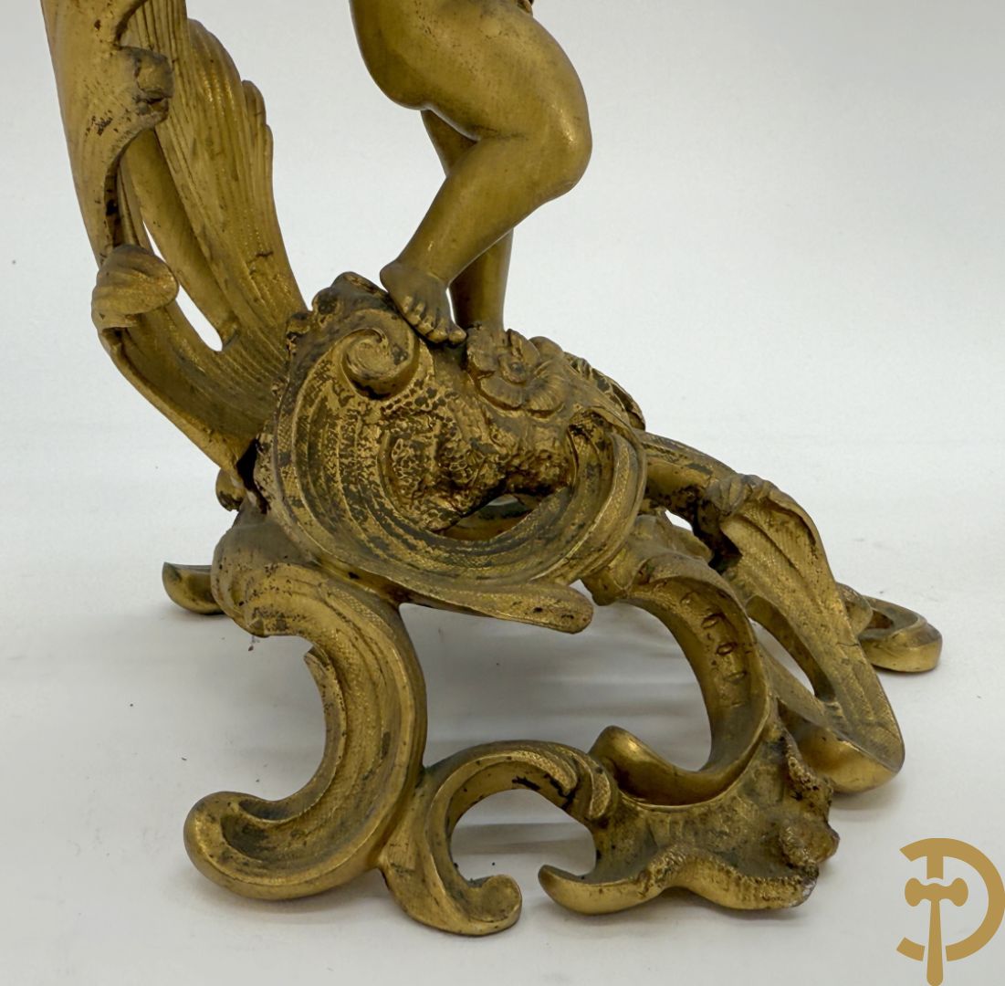 Driedelige vuurvergulde bronzen garnituur, Louis XV stijl, bestaande uit middenstuk met klok omgeven door musicerende cupido