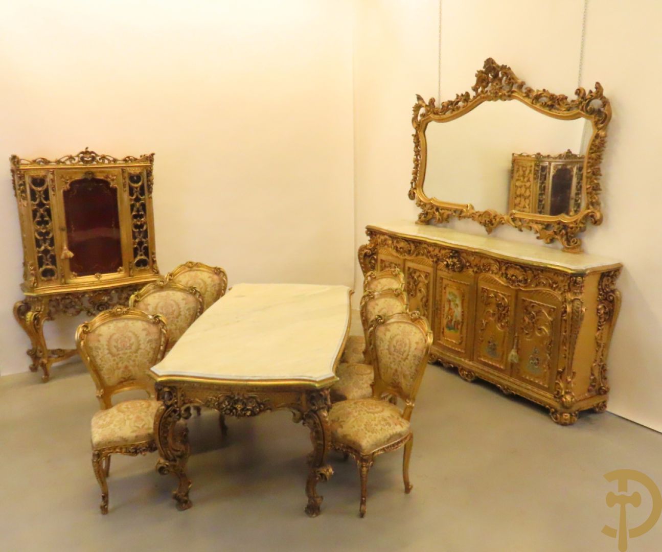 Uitzonderlijke vergulde Louis XV eetkamer bestaande uit vijfdeursdressoir met voluutvormige accanthusranken en rocailles, beschilderd met bloemenmotieven en centraal tafererel met hoornen des overvloeds + bijhorende spiegel vergulde tafel op voluutvormige poten met zes bijhorende stoelen + vitrine met accanthusranken en centrale deur, op voluutvormige poten