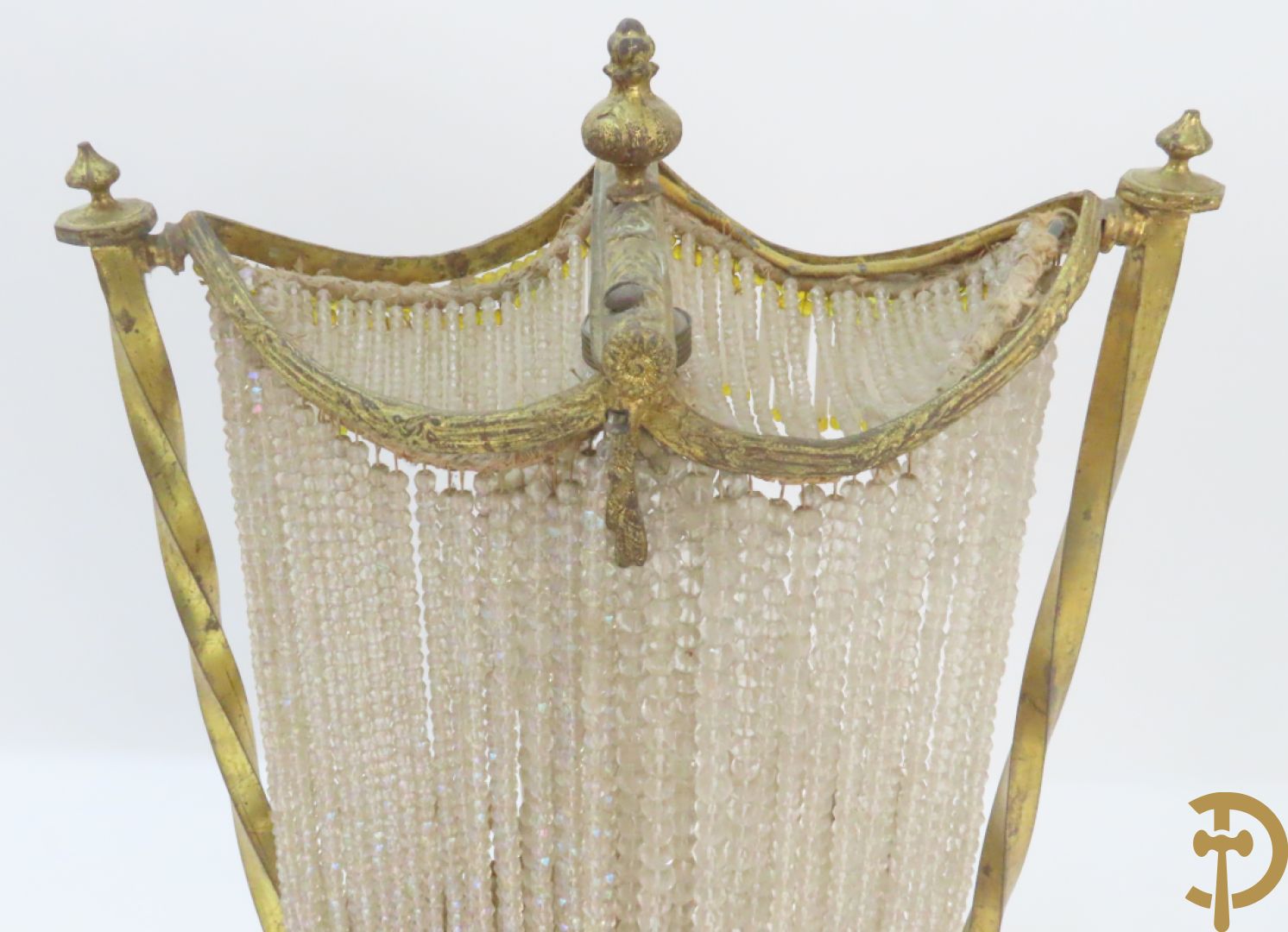 Lieftallig biscuit van romantisch koppel bij amfoor met kleine neergezeten cupido onder koperen baldakijn met kristallen belletjes