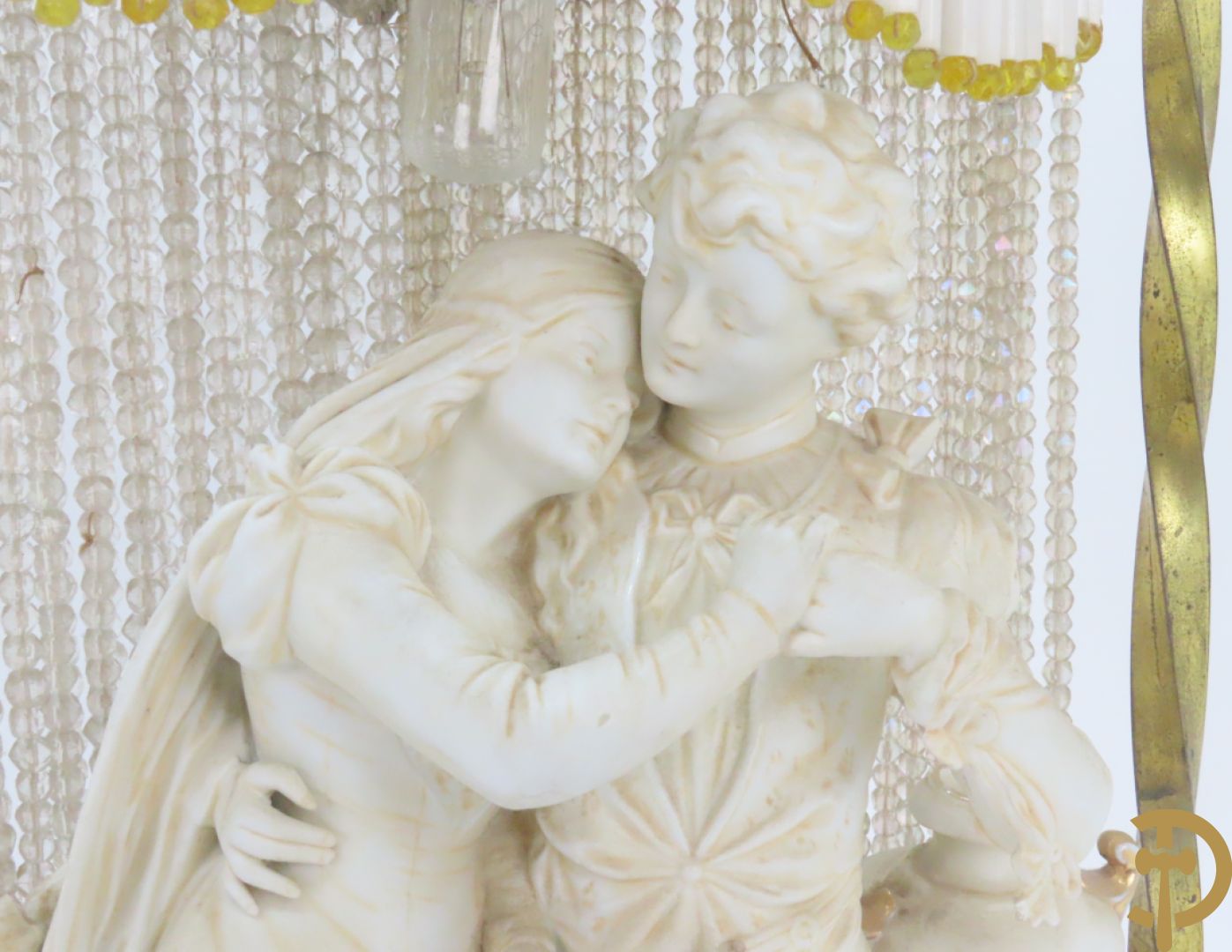 Lieftallig biscuit van romantisch koppel bij amfoor met kleine neergezeten cupido onder koperen baldakijn met kristallen belletjes