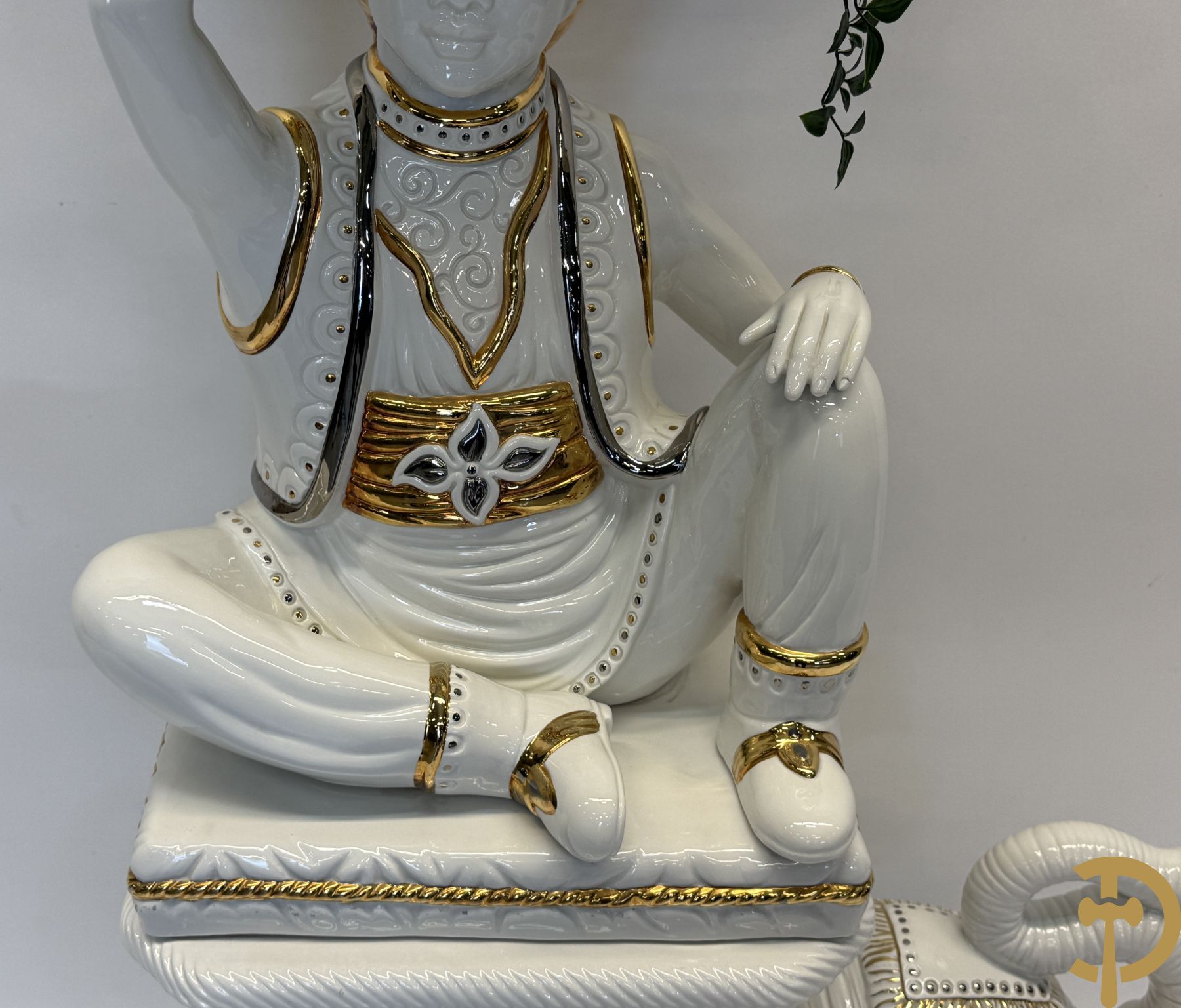 Porseleinen sierbeeld van olifant als staander met daarboven jongeman met bloemencachepot