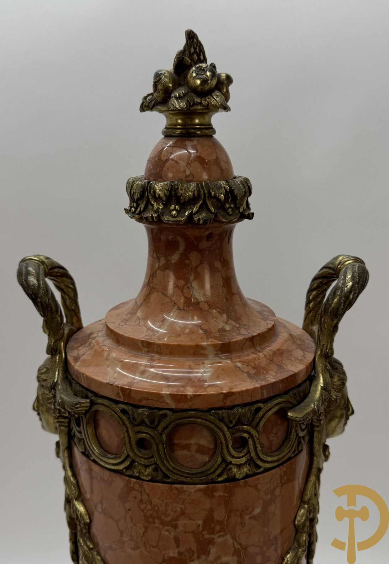 Paar oranje/rode marmeren cassolettes, zijdelings bezet met dameshoofden dragende een guirlande van bloemen - bovenaan met bloementroffee